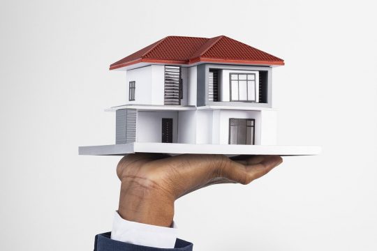 Hand holding house real estate and property model